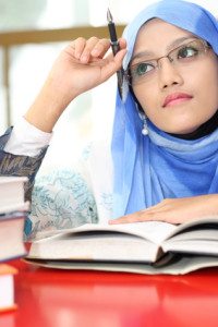 A young muslim girl reading a book while thinking