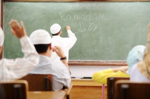 Teacher at classroom writing Ramadan on board