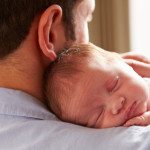 Father At Home With Sleeping Newborn Baby Daughter