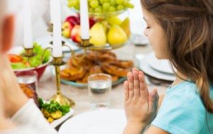 family, holiday, religion, tradition and people concept - close up of girl praying at dinner at home