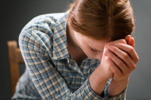 Closeup portrait of a young woman spending time in prayer on a wooden chair. ** Note: Shallow depth of field